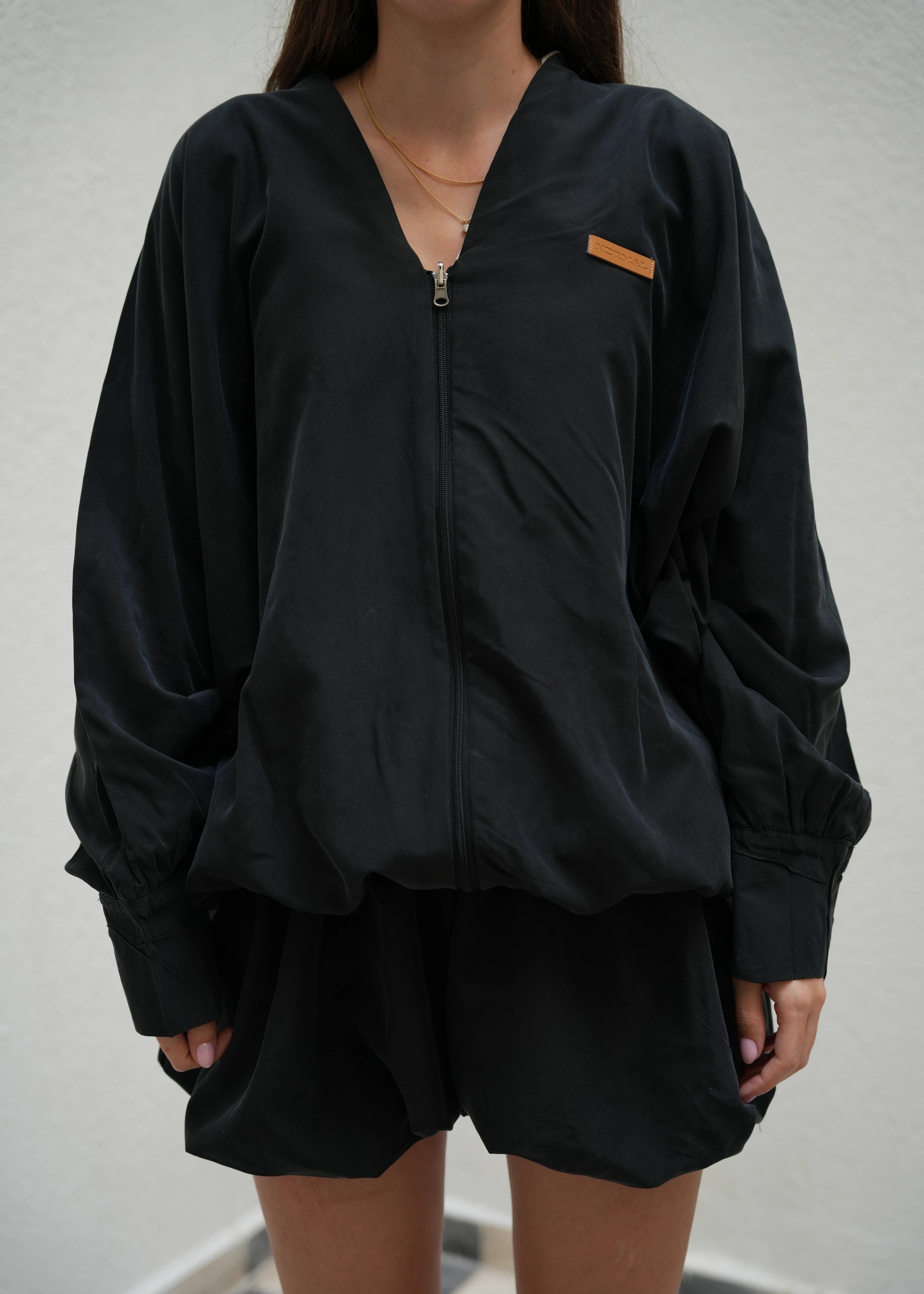 Person wearing a black jacket with a brand logo on a white background