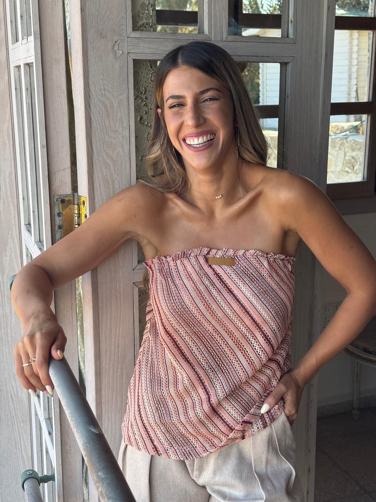 Woman wearing a strapless pink top standing indoors.