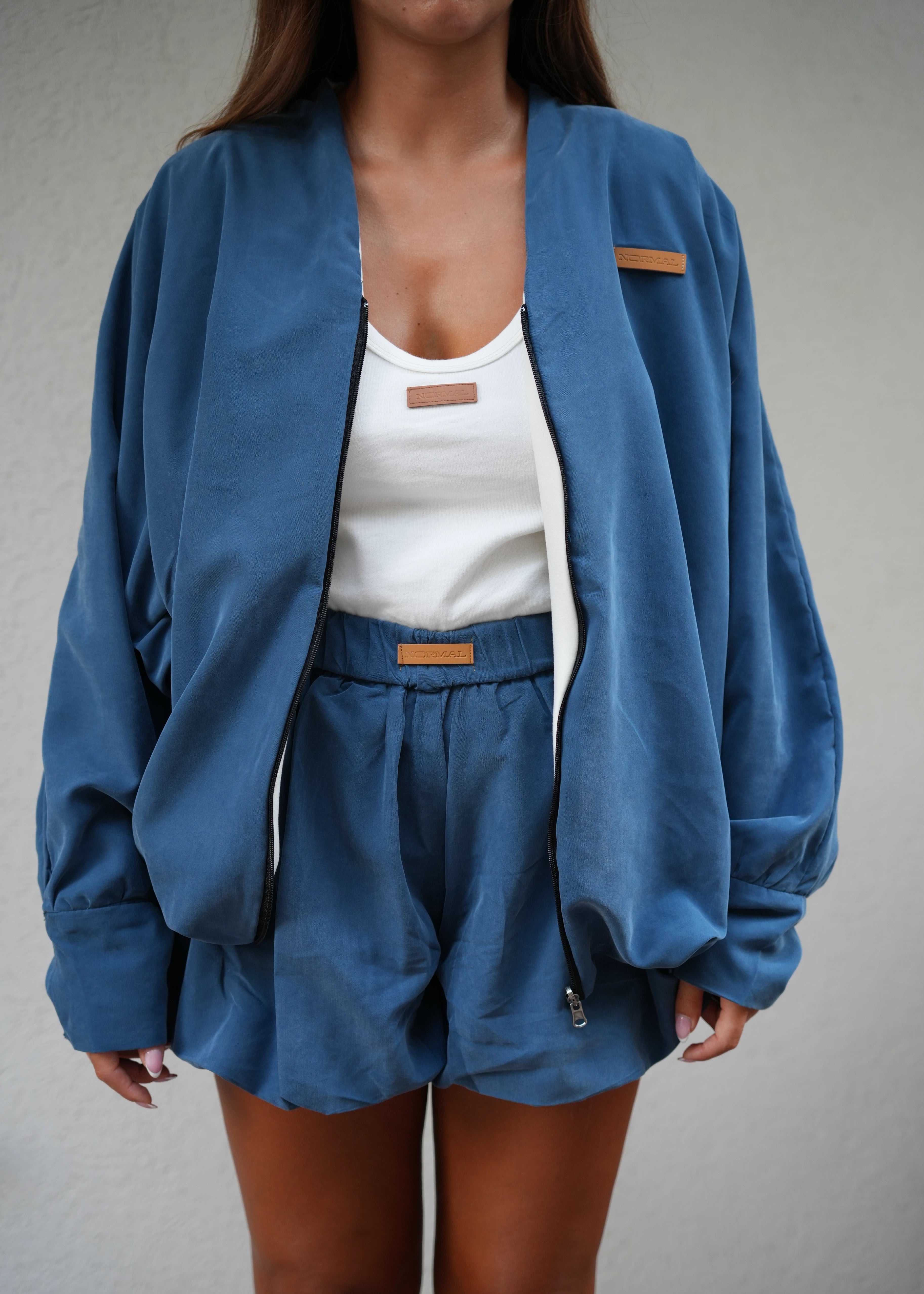 Person wearing a blue jacket with a neutral background