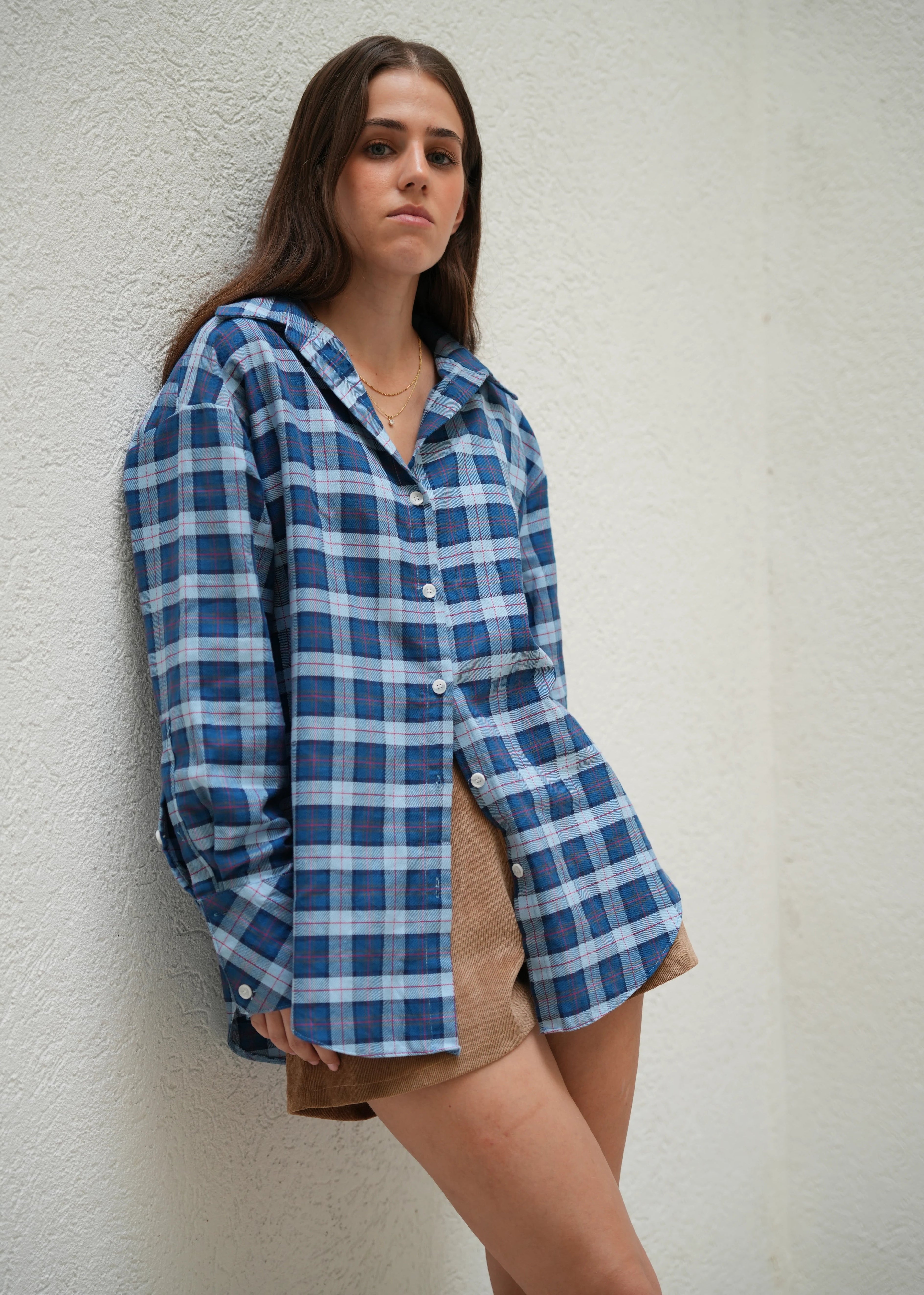 Person wearing a blue and white plaid shirt against a plain background