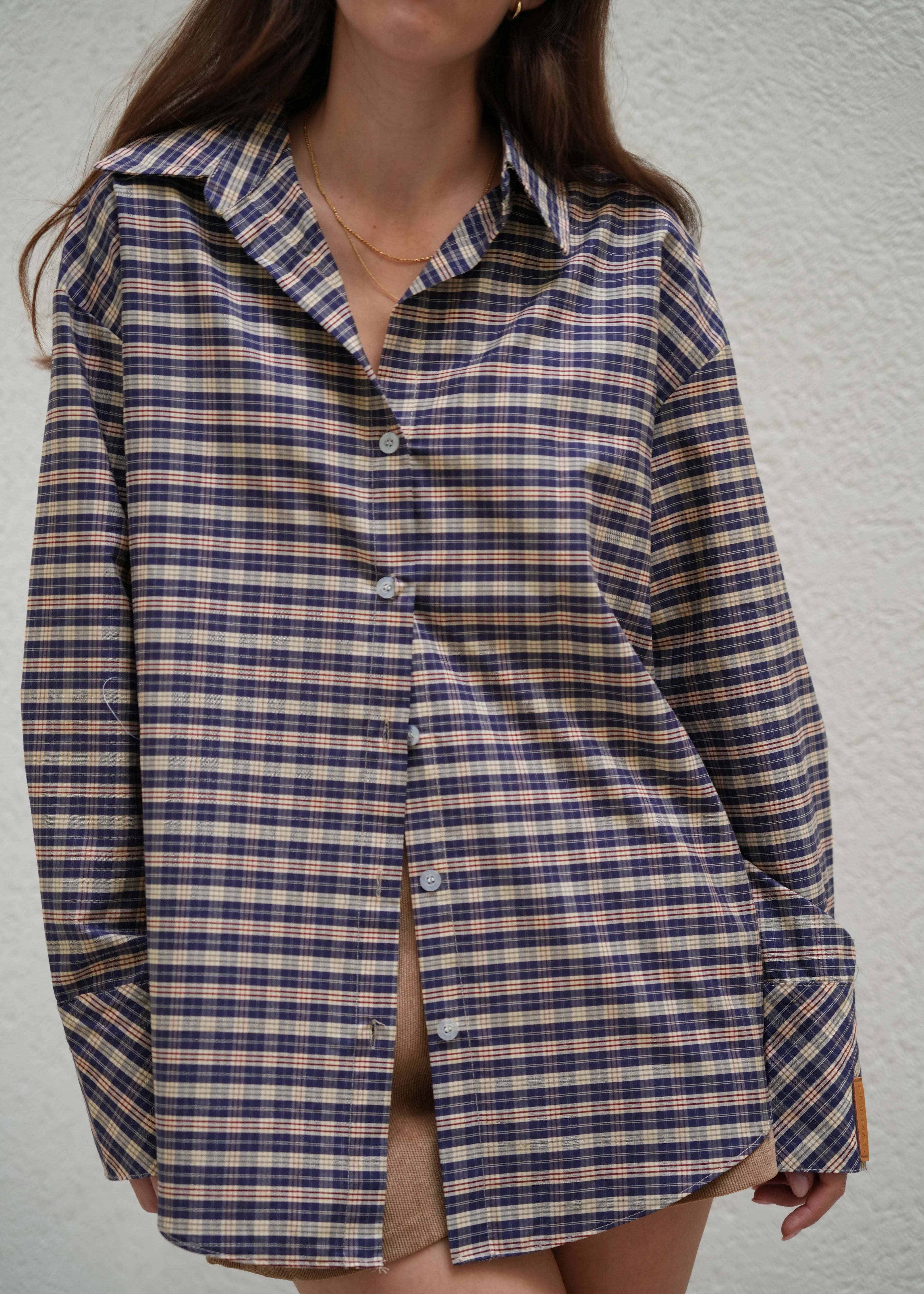 Person wearing a blue and white checkered shirt against a plain background
