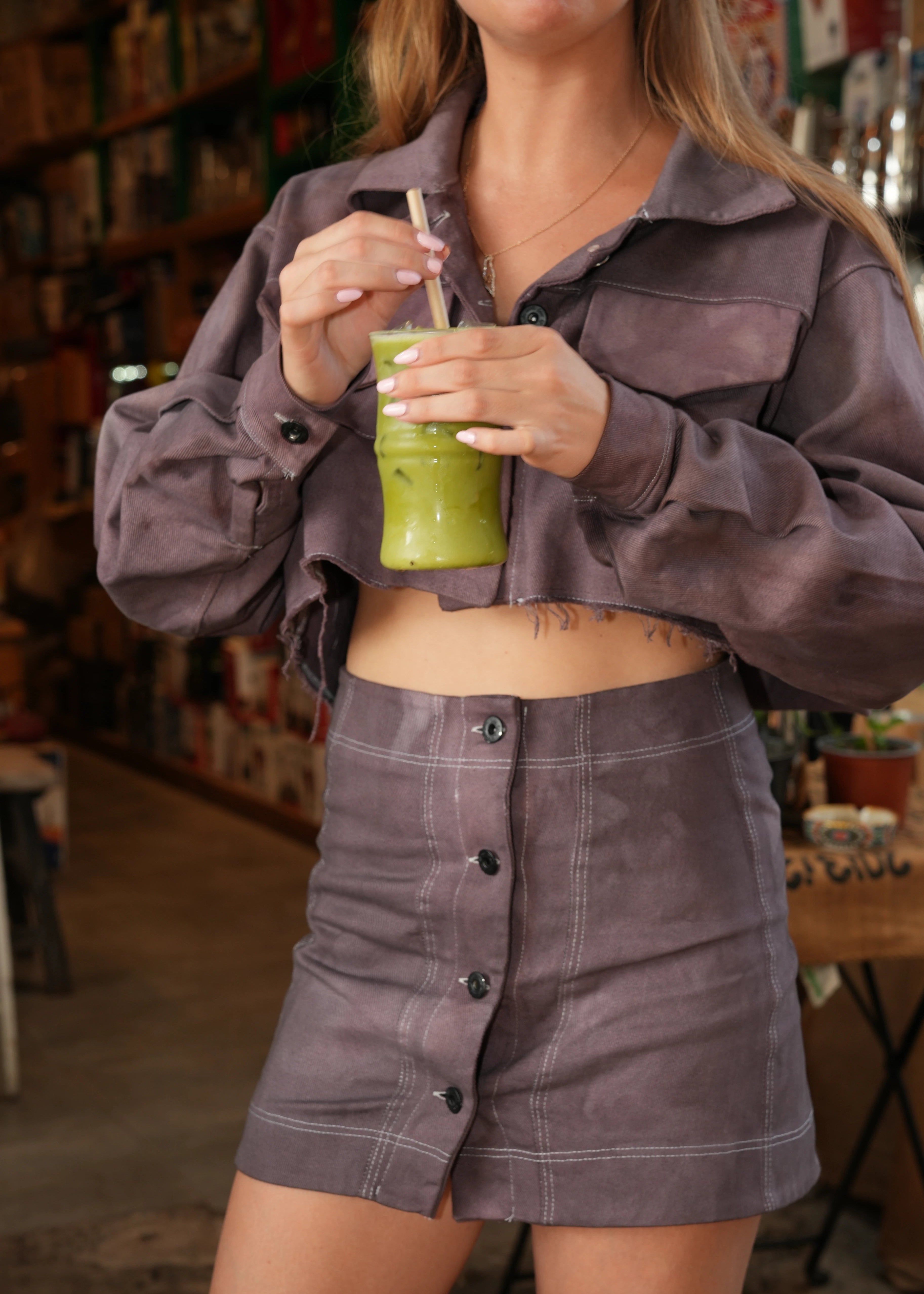 Person wearing a gray shirt holding a green cup with a straw in an indoor setting
