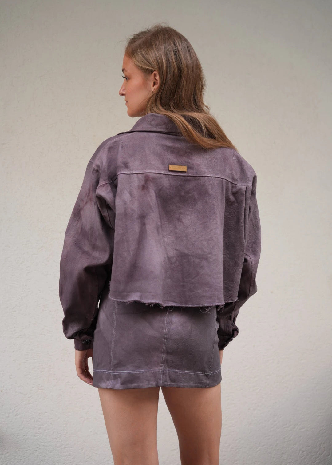 Person wearing a purple jacket on a plain background